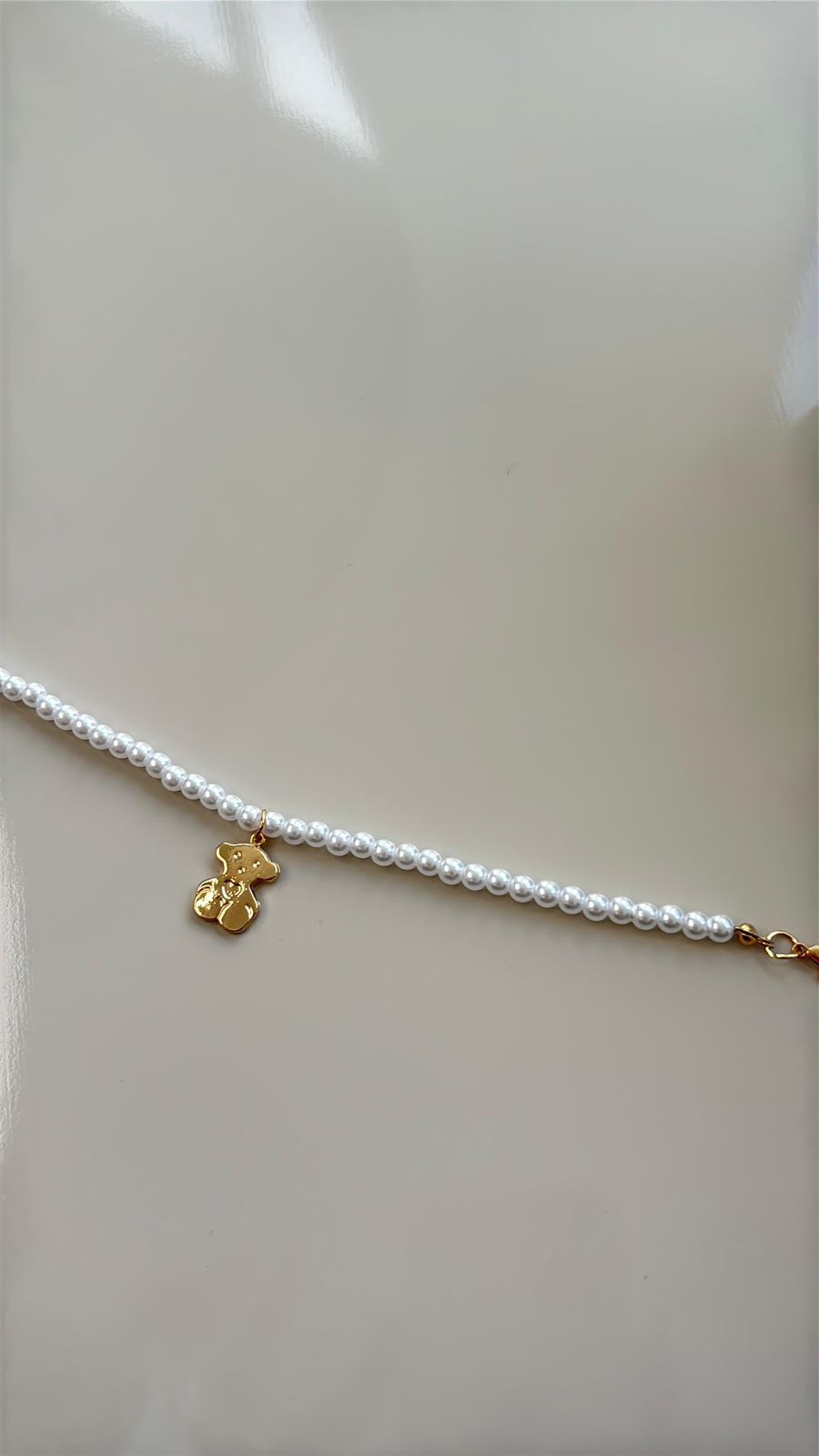 pulseira pérola com pingente de ursinho dourado