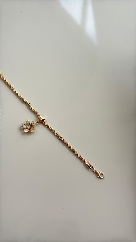 pulseira em corrente dourada com pingente de flor cravejada