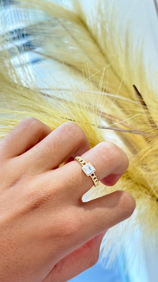 anel dourado estilo solitário com pedra quadrada e detalhe vazado no anel