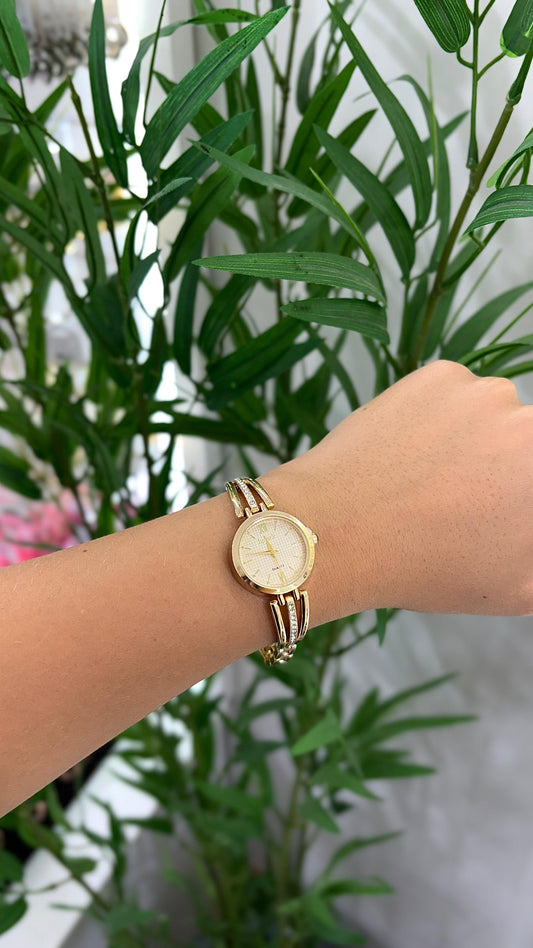 relógio dourado minimalista com detalhes de strass na pulseira